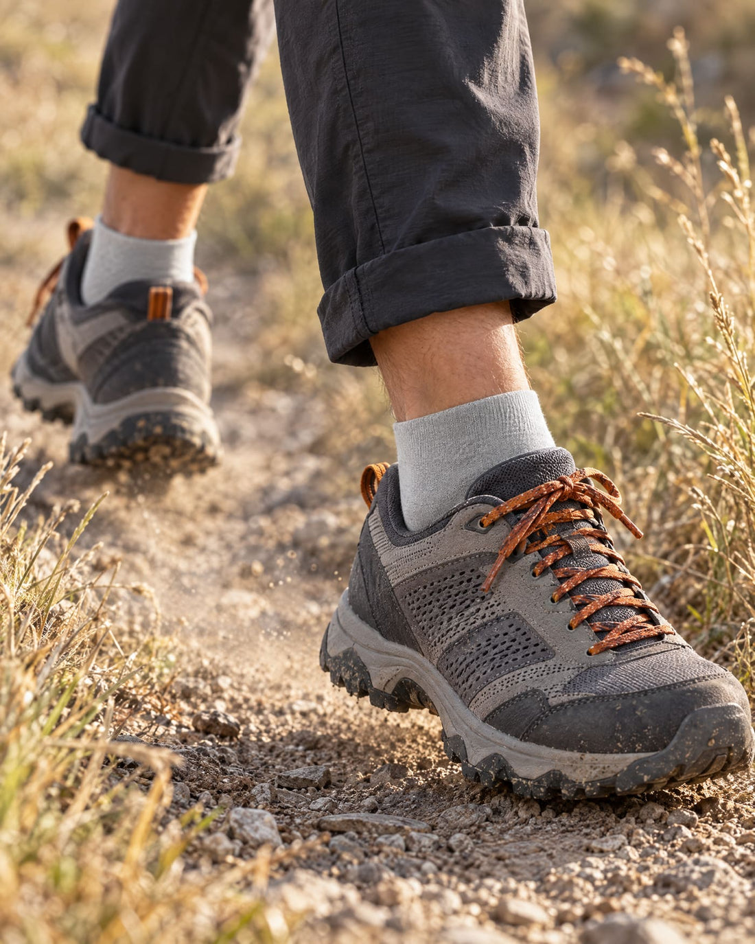 Piernas de un senderista caminando por un sendero con zapatillas de trail y calcetín gris
